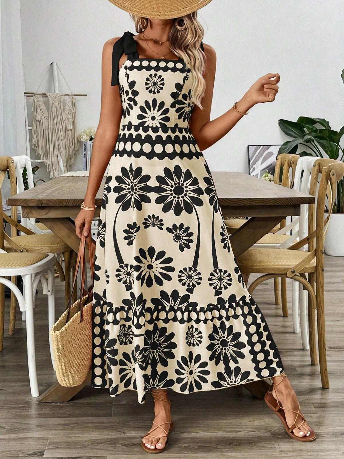 Woman wearing a cream and black floral print maxi dress with tie shoulder straps