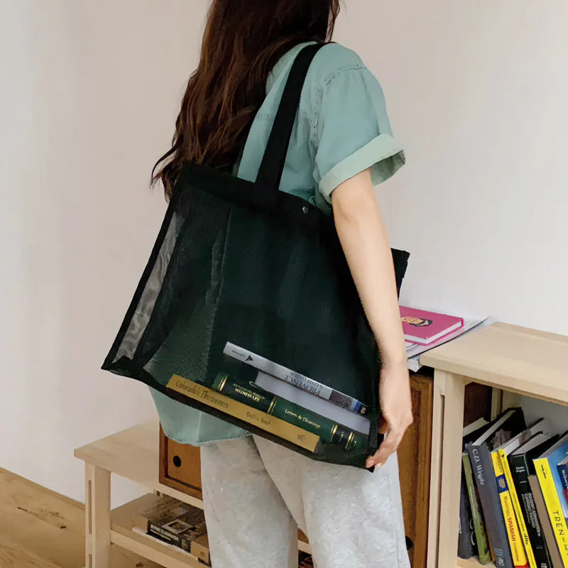 Woman carrying the black sheer mesh bag with books inside, back view