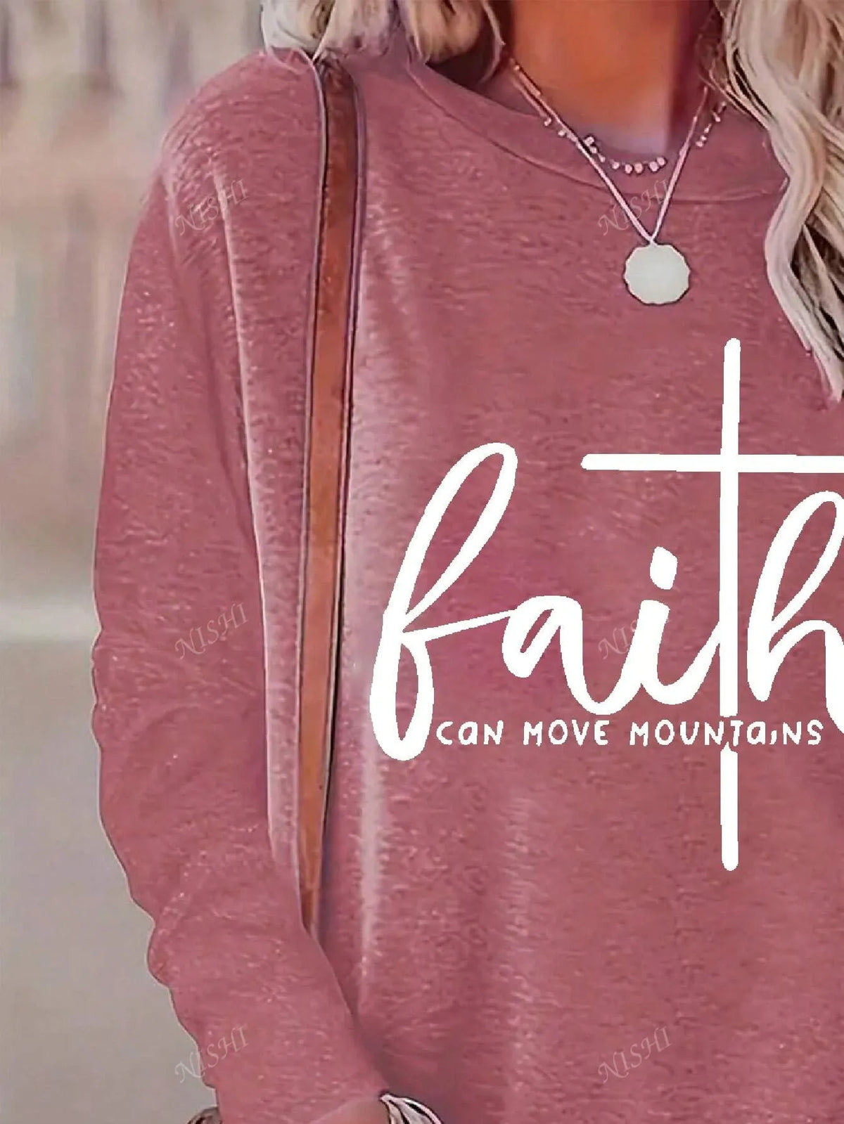 Close-up of the white faith cross graphic on the coral pink long-sleeve tee