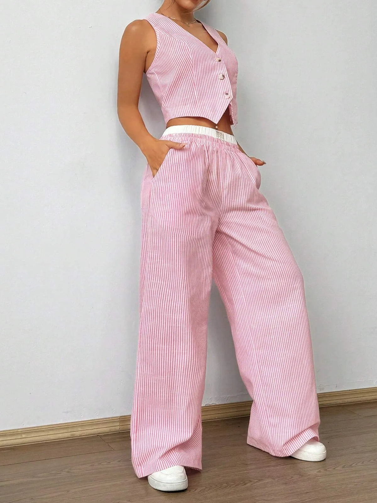 Woman in the pink pinstripe vest top and wide-leg pants, hands in the pockets, front view