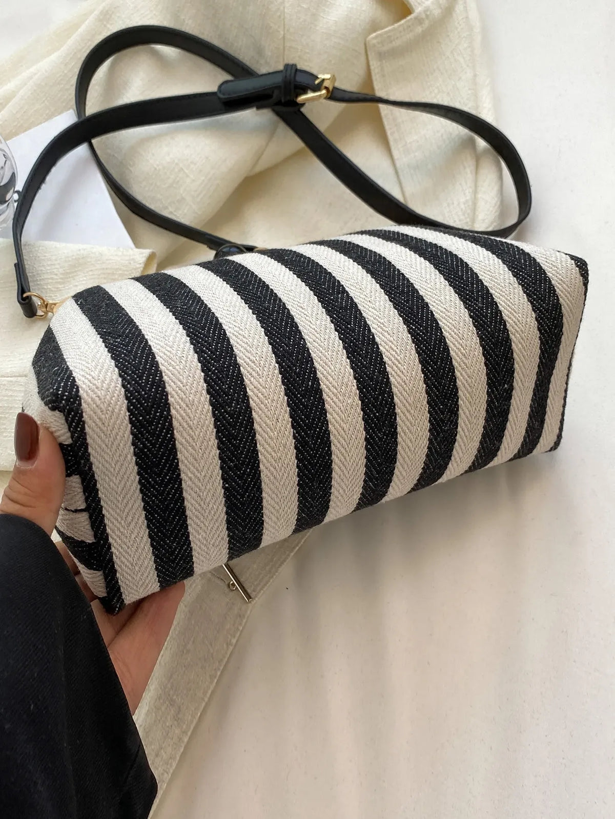 Black and cream striped bag held on its side to show the canvas body and black shoulder strap