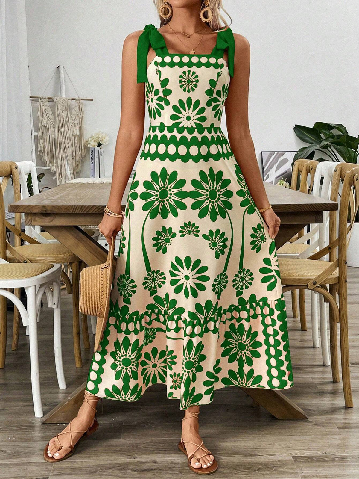 Woman wearing a cream and green floral print maxi dress with tie shoulder straps
