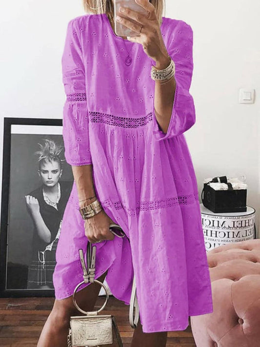 Woman wearing a violet tiered eyelet dress with lace trim and three-quarter sleeves