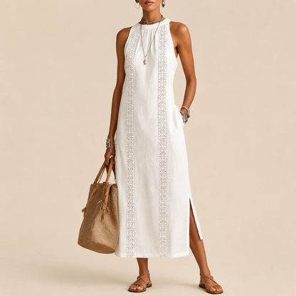 White sleeveless dress with an embroidered lace panel and a side slit, front view with a tan tote bag