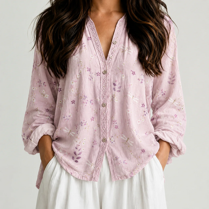 Woman wearing a pale pink floral boho V-neck blouse with white pants