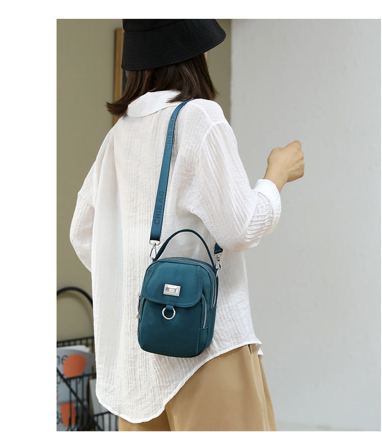 Woman carrying the small teal shoulder bag, back view