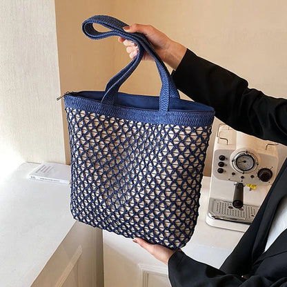 Hand holding the navy blue open-weave tote bag