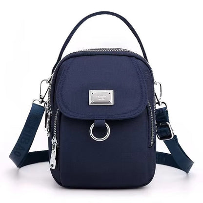 Small navy blue shoulder bag with front flap pocket, front view