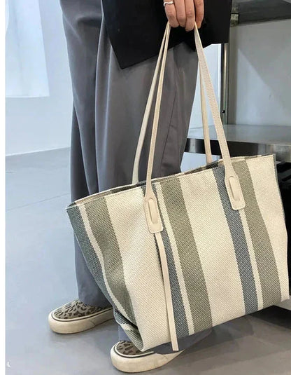 Person holding the gray and cream striped canvas tote by its handles