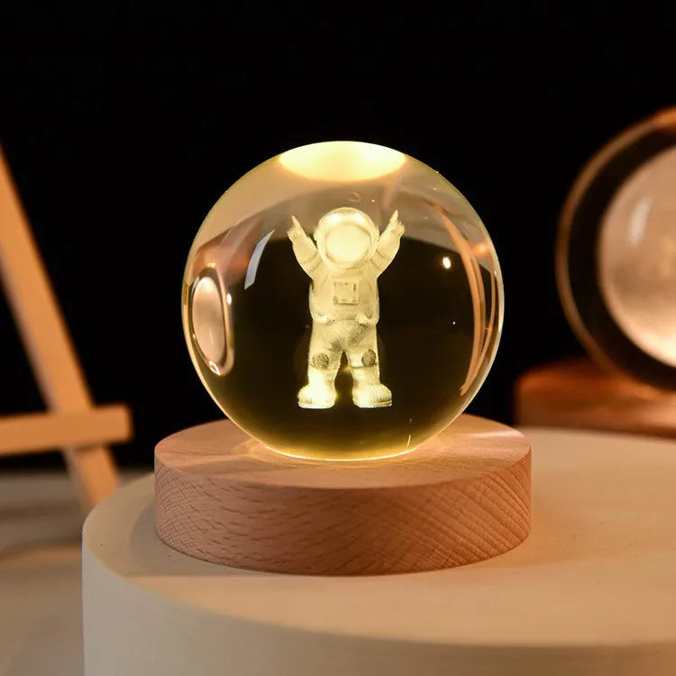 Crystal ball night light with an astronaut figure inside, glowing on a wooden base