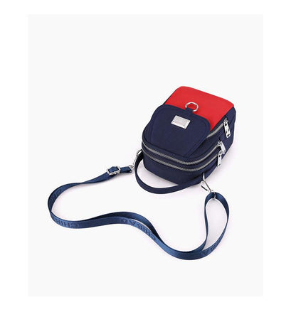 Navy and red shoulder bag lying flat with its adjustable strap