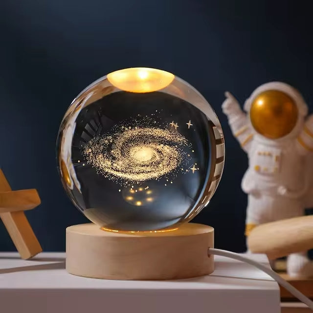 Crystal ball night light with a spiral galaxy design inside, on a wooden base