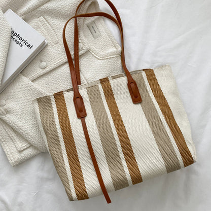 Brown and cream striped canvas tote laid flat on a white jacket