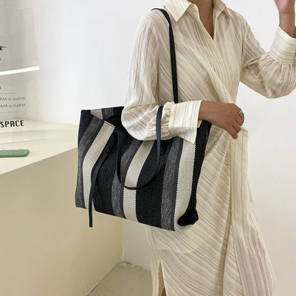 Woman carrying the black, gray and white striped canvas tote on her shoulder
