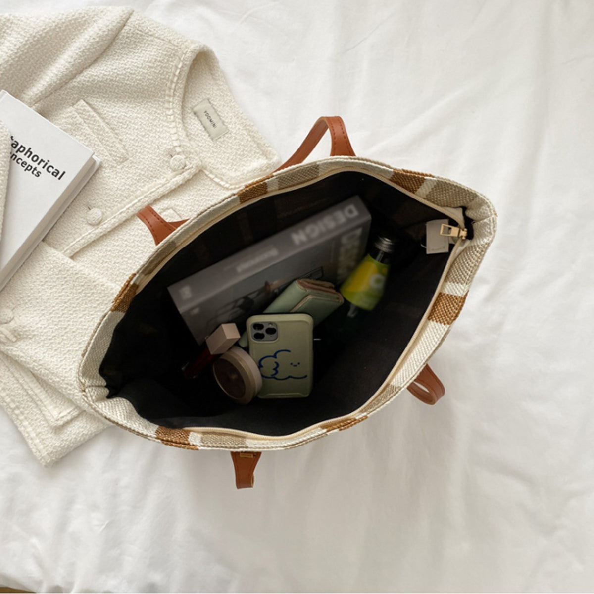Open striped canvas tote showing the black lining holding a phone, book and everyday items