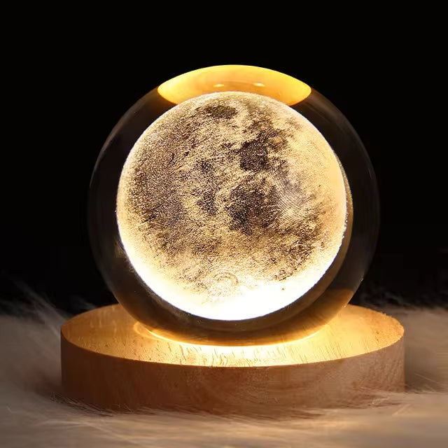 Crystal ball night light with a full moon design inside, glowing warm on a wooden base