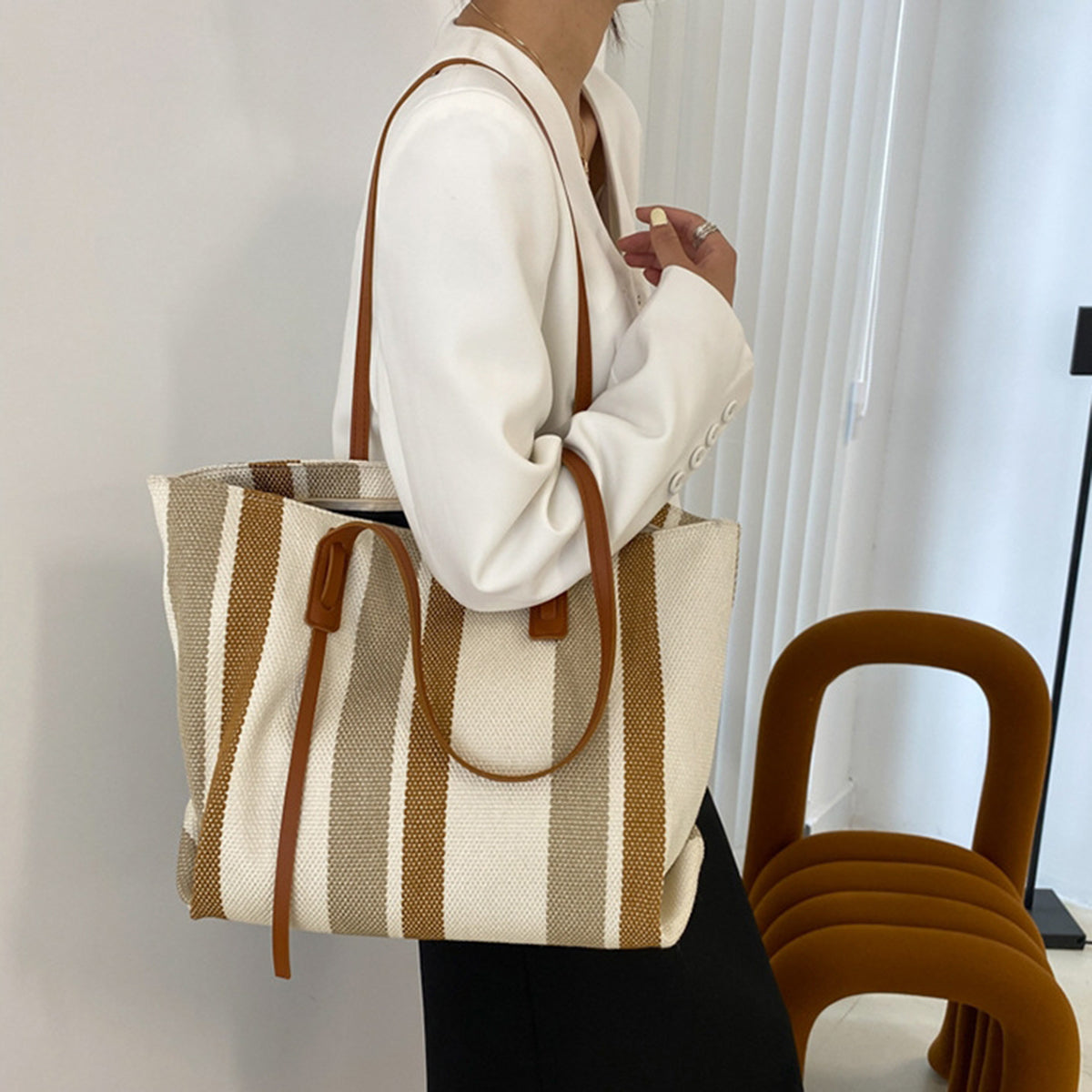 Woman carrying the brown and cream striped canvas tote on her shoulder