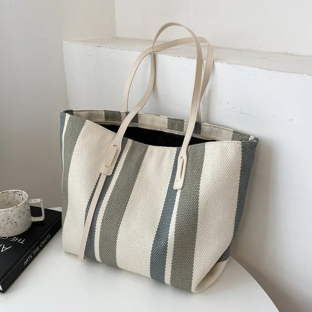Gray and cream striped canvas tote with cream handles on a white table