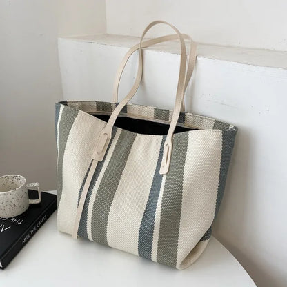 Gray and cream striped canvas tote with cream handles on a white table