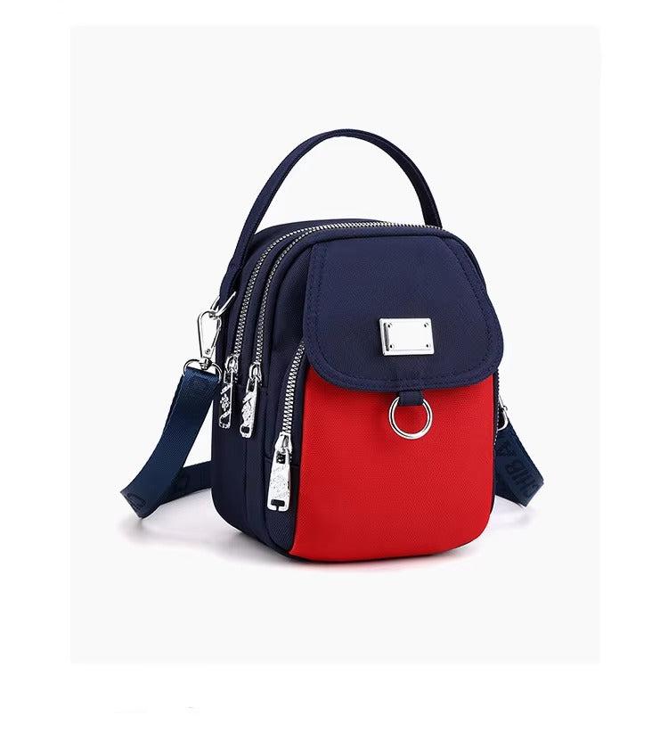 Small navy and red multi-zip shoulder bag, angled front view