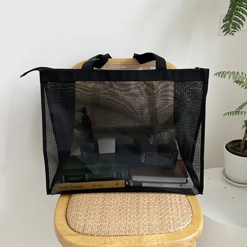 Black sheer mesh bag on a rattan chair, holding books and small items