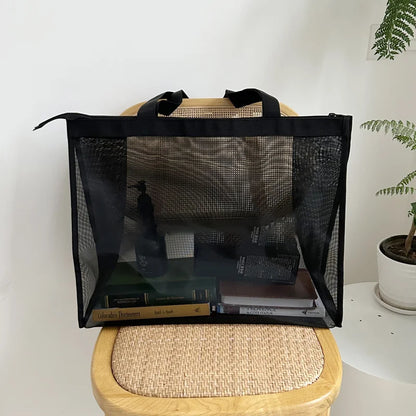 Black sheer mesh bag on a rattan chair, holding books and small items