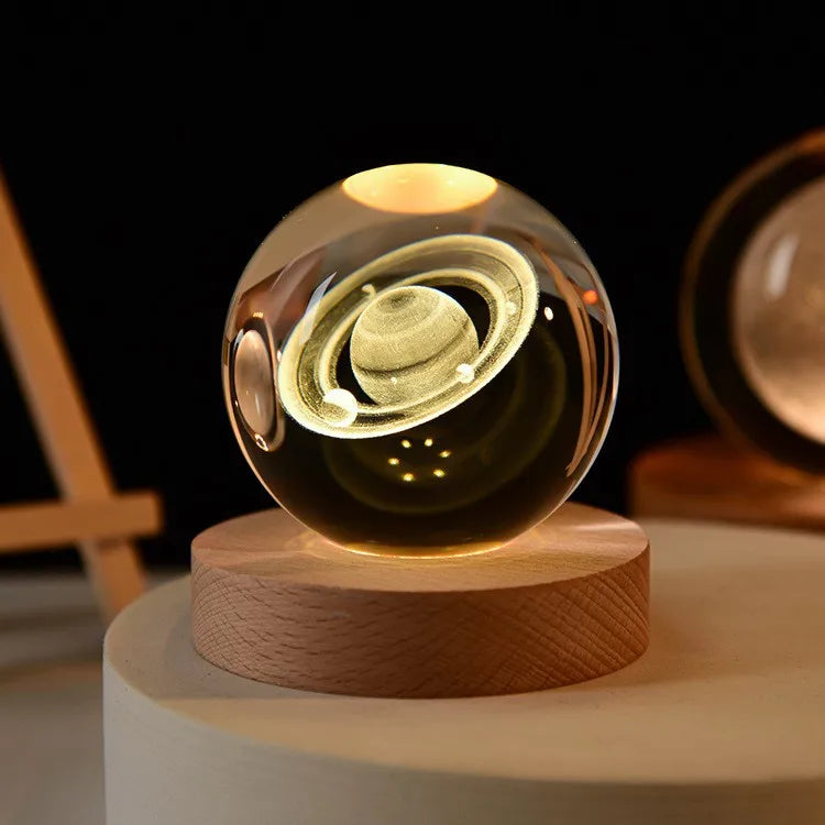Crystal ball night light with a planet Saturn design inside, glowing on a wooden base