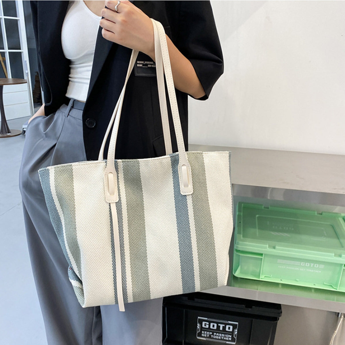 Woman holding the blue-gray and cream striped canvas tote with cream handles