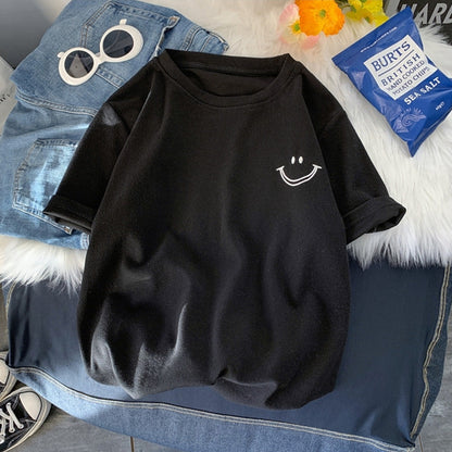 Black casual T-shirt with an embroidered smile face, laid flat on denim