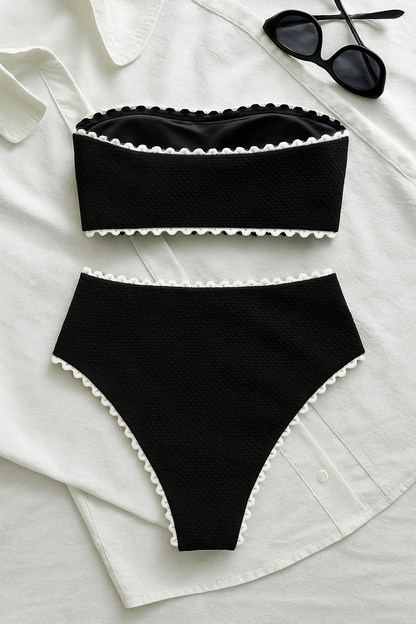 Black textured bandeau top and high-waist bikini bottom with white trim, laid flat on a white shirt