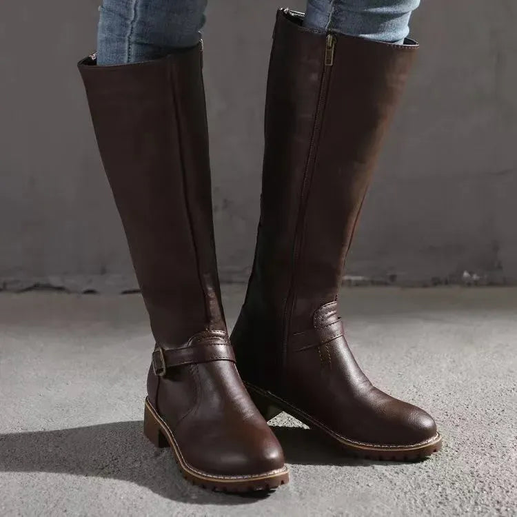 Dark brown knee-high boots with a buckle strap and side zipper, worn with jeans
