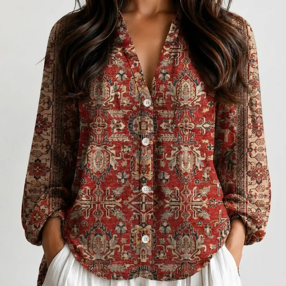 Woman wearing a red and rust printed boho V-neck blouse with white pants