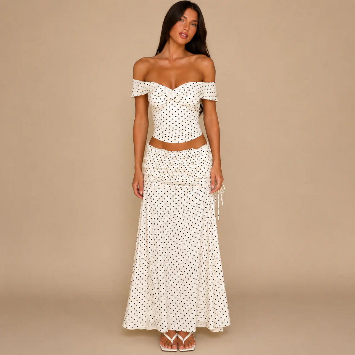 Woman wearing a cream polka dot off-the-shoulder crop top and matching maxi skirt, front view
