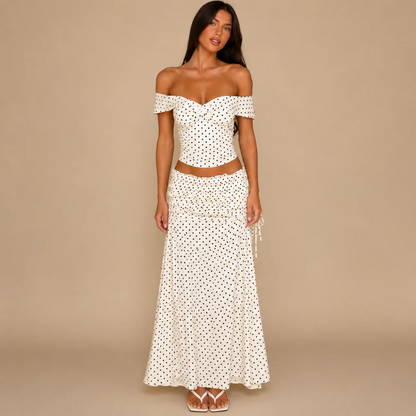 Woman wearing a cream polka dot off-the-shoulder crop top and matching maxi skirt, front view