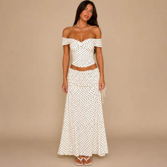 Woman wearing a cream polka dot off-the-shoulder crop top and matching maxi skirt, front view