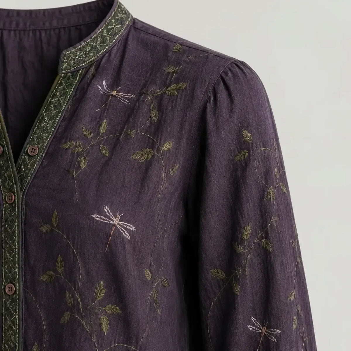 Close-up of the dark purple blouse neckline with green embroidered trim and floral print