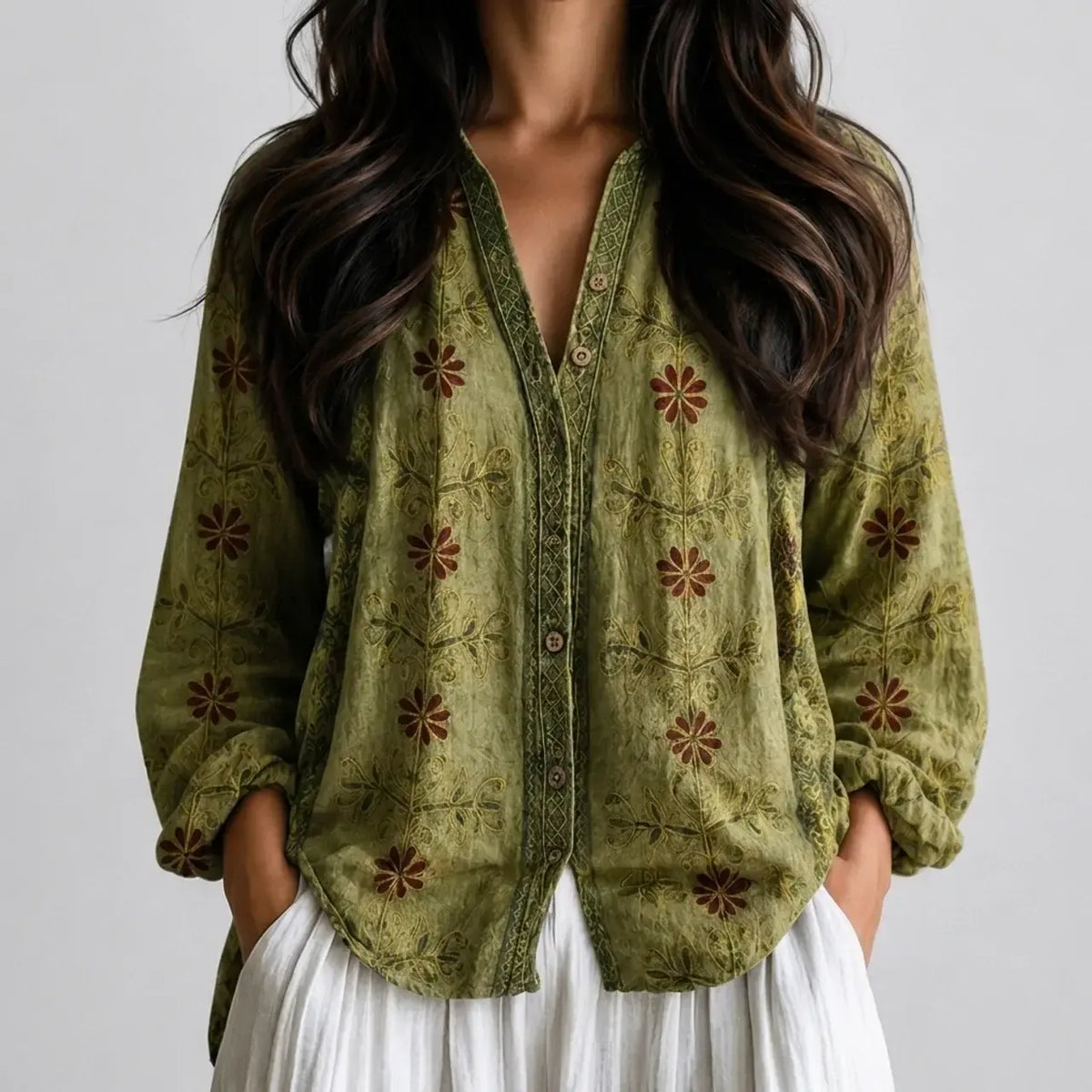 Woman wearing an olive green embroidered boho V-neck blouse with white pants