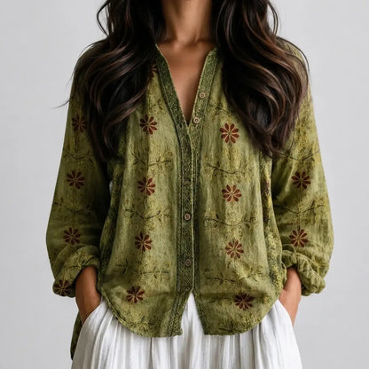 Woman wearing an olive green embroidered boho V-neck blouse with white pants