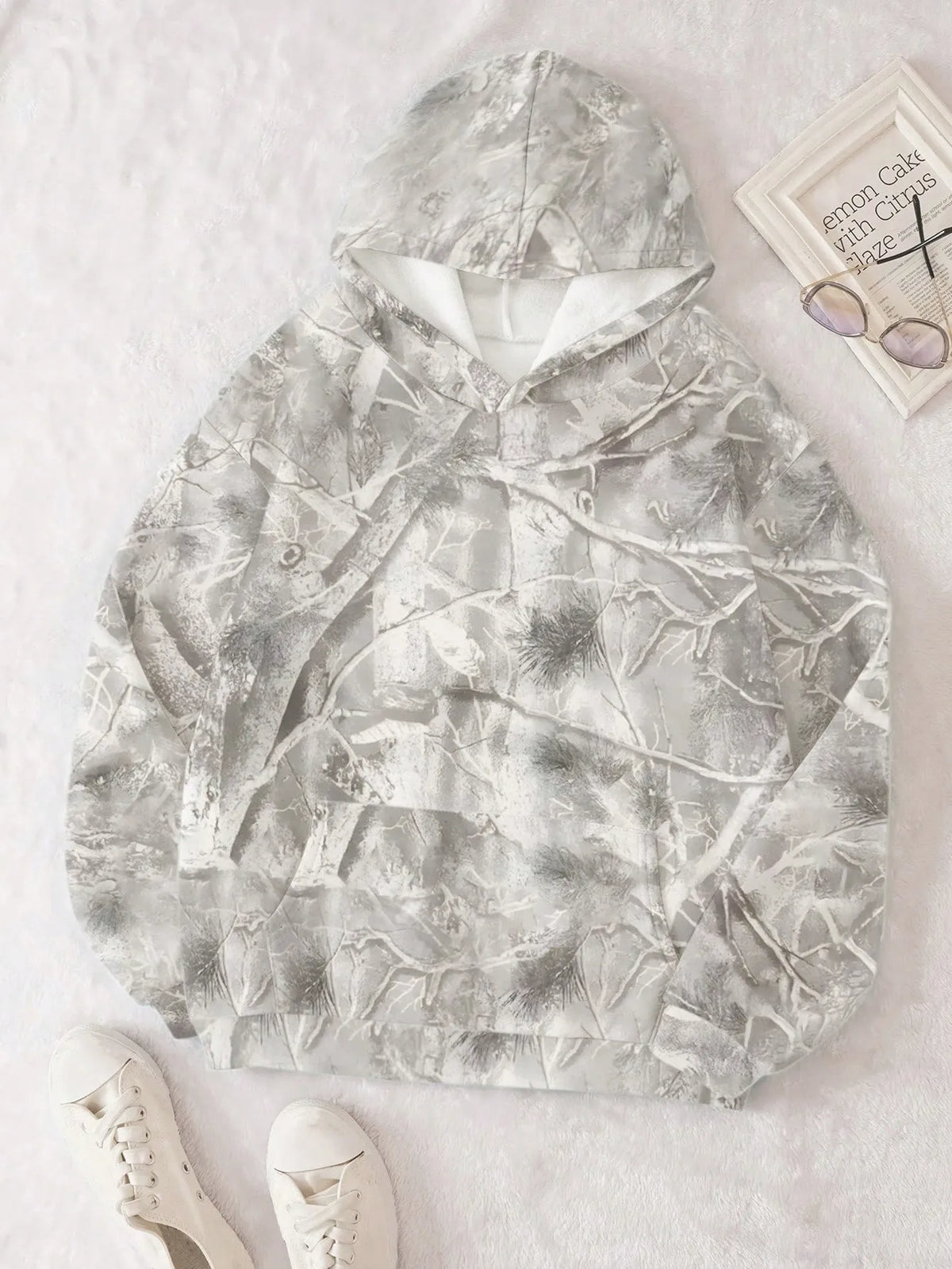 Light grey branch print oversized hoodie laid flat with sneakers and sunglasses nearby
