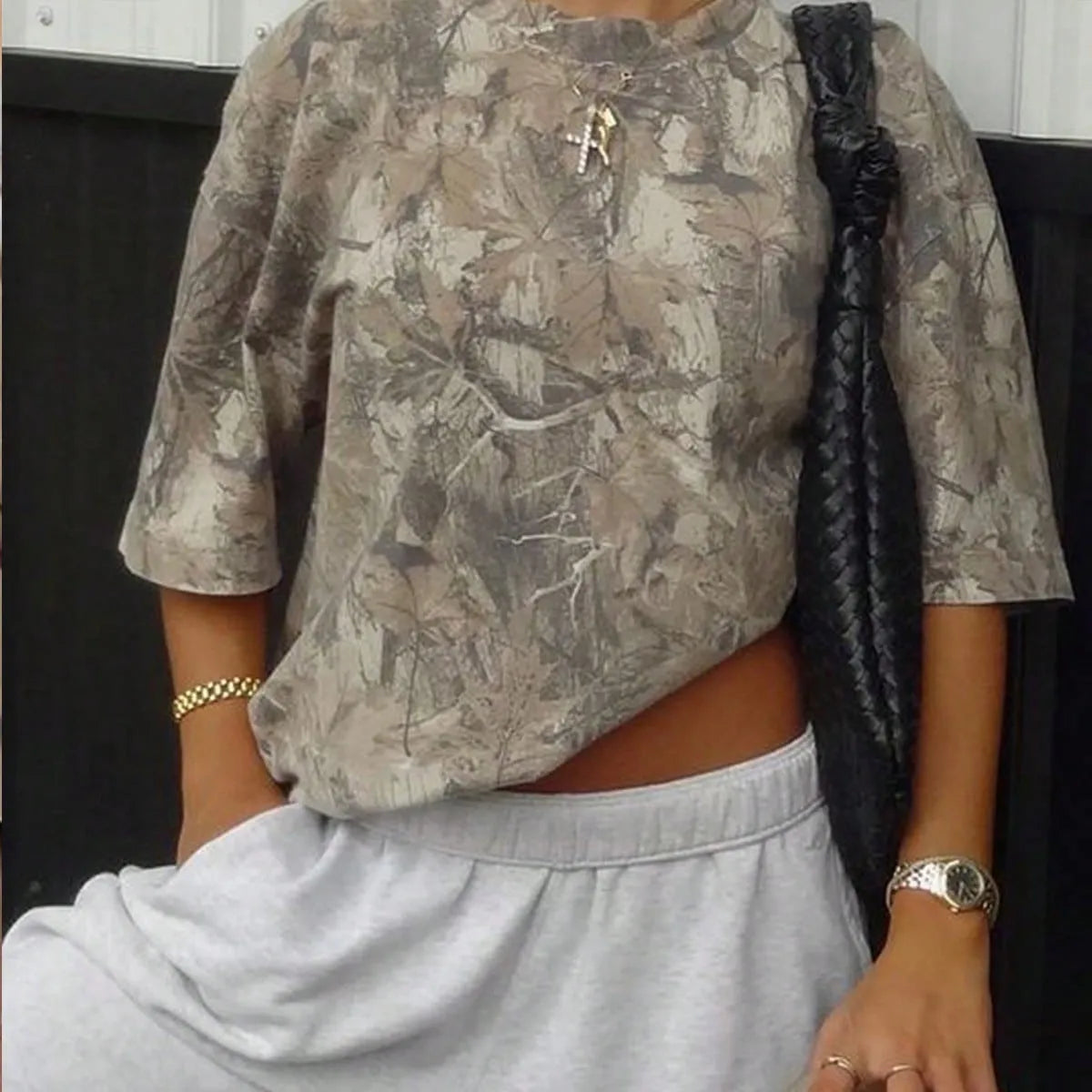 Close view of the oversized olive camo print T-shirt with a black shoulder bag
