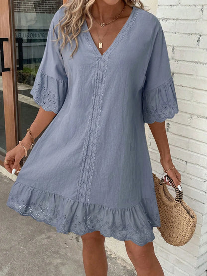 Woman wearing the light blue V-neck dress with a ruffled hem and a woven straw bag
