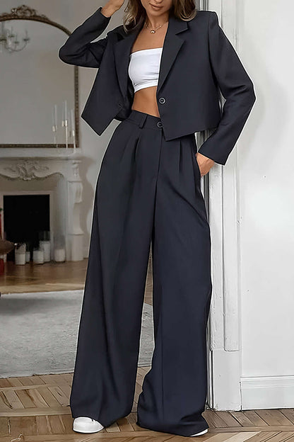 Black cropped blazer with a white top and wide-leg high-waist black trousers, full-length front view
