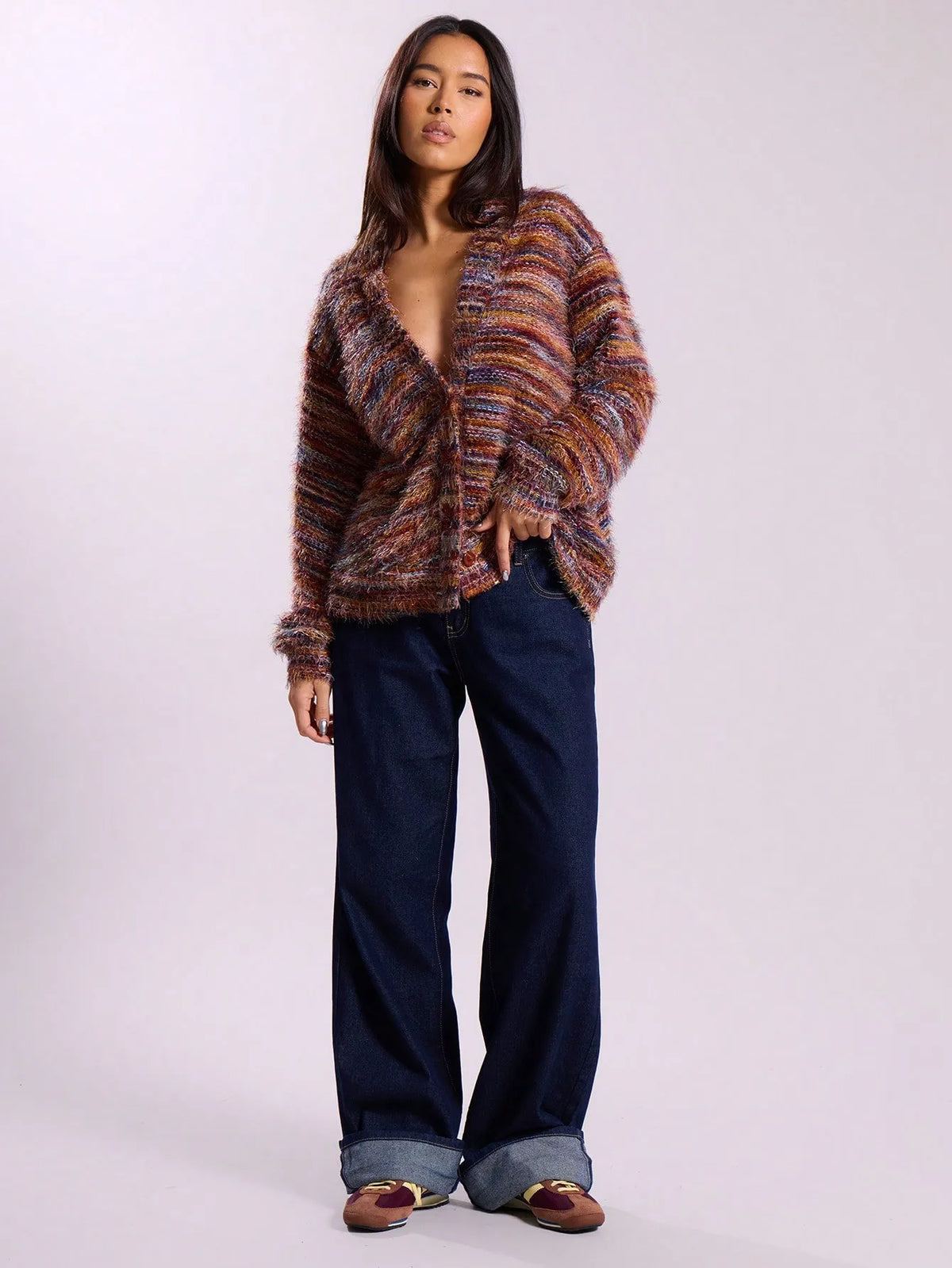 Woman wearing the multicolor striped knit cardigan open with wide-leg dark jeans, full-length view