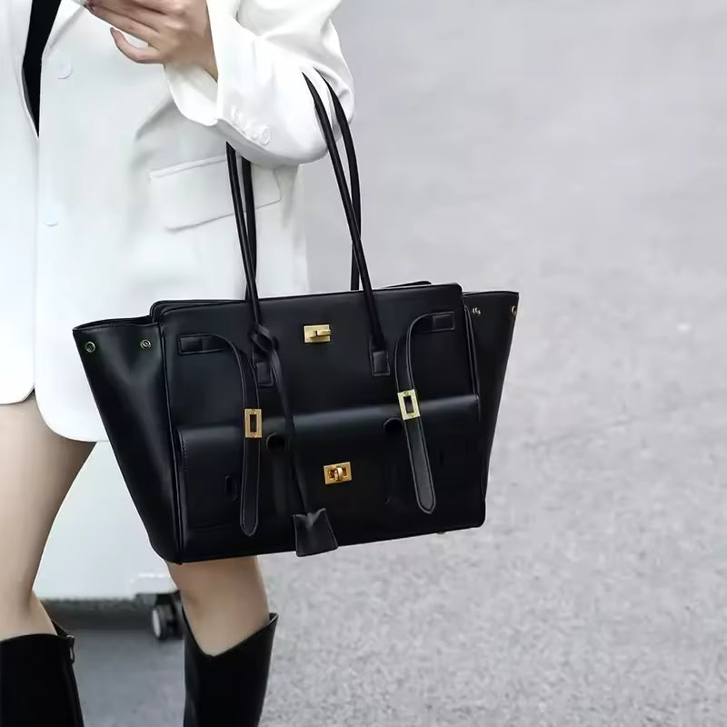 Woman carrying the black tote bag on her arm, worn with a white blazer and black boots