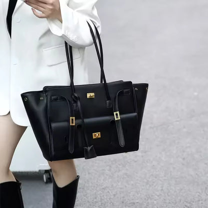 Woman carrying the black tote bag on her arm, worn with a white blazer and black boots