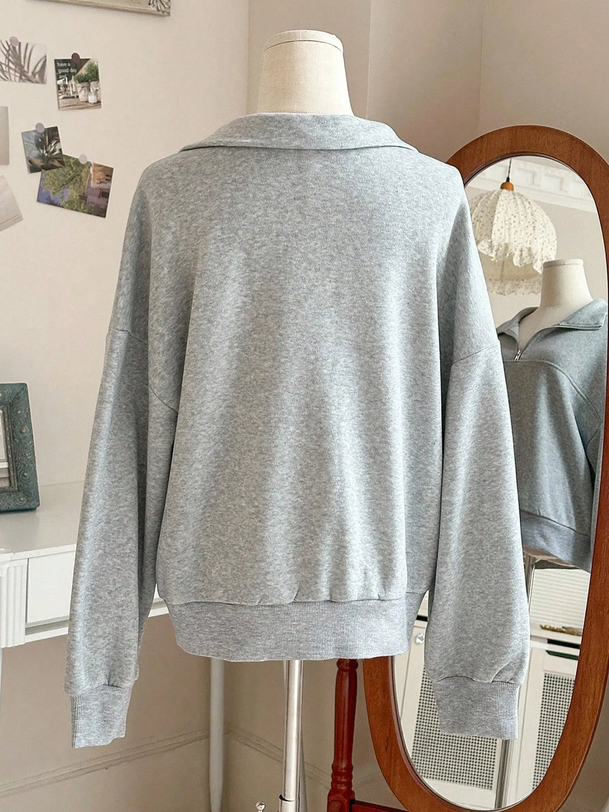 Back view of the light grey oversized quarter-zip sweatshirt with a ribbed hem on a mannequin