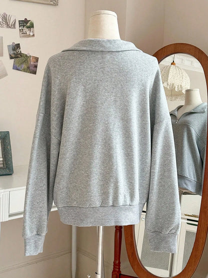 Back view of the light grey oversized quarter-zip sweatshirt with a ribbed hem on a mannequin