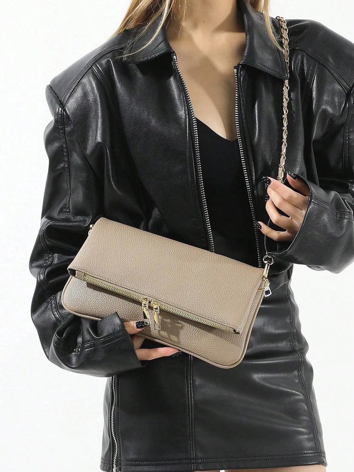 Woman holding the taupe fold-over bag with a gold chain strap, front view