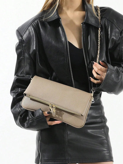 Woman holding the taupe fold-over bag with a gold chain strap, front view
