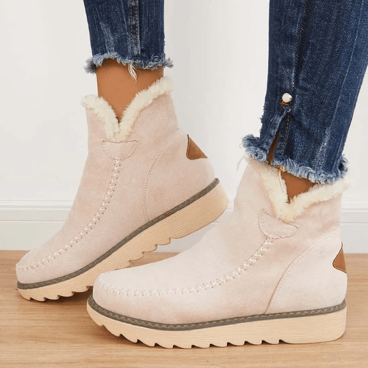 Beige suede winter ankle boots with fluffy fleece trim and a cream rubber sole, worn with cuffed jeans